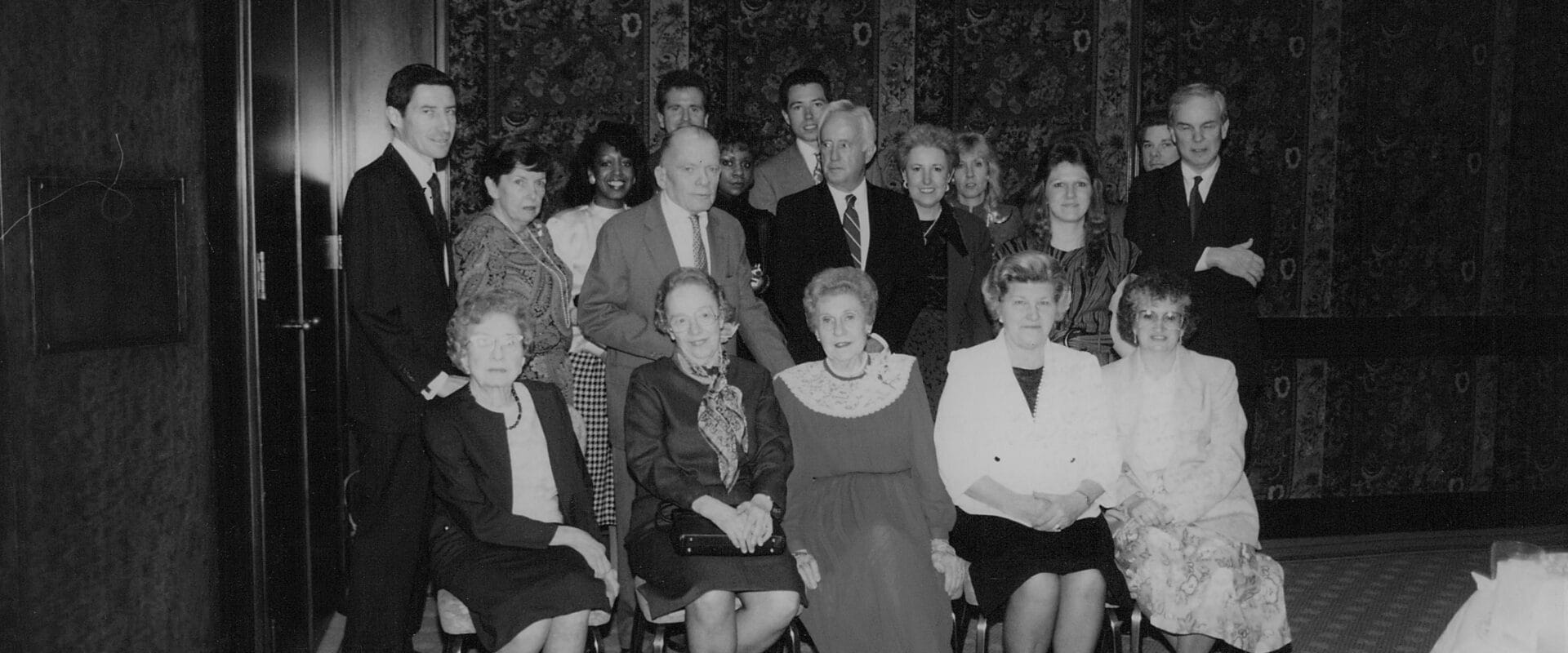 A photo from the 1980s. It shows 17 HWP staff members posed for a photo. 5 ladies are seated in the front, and the rest are standing behind them.