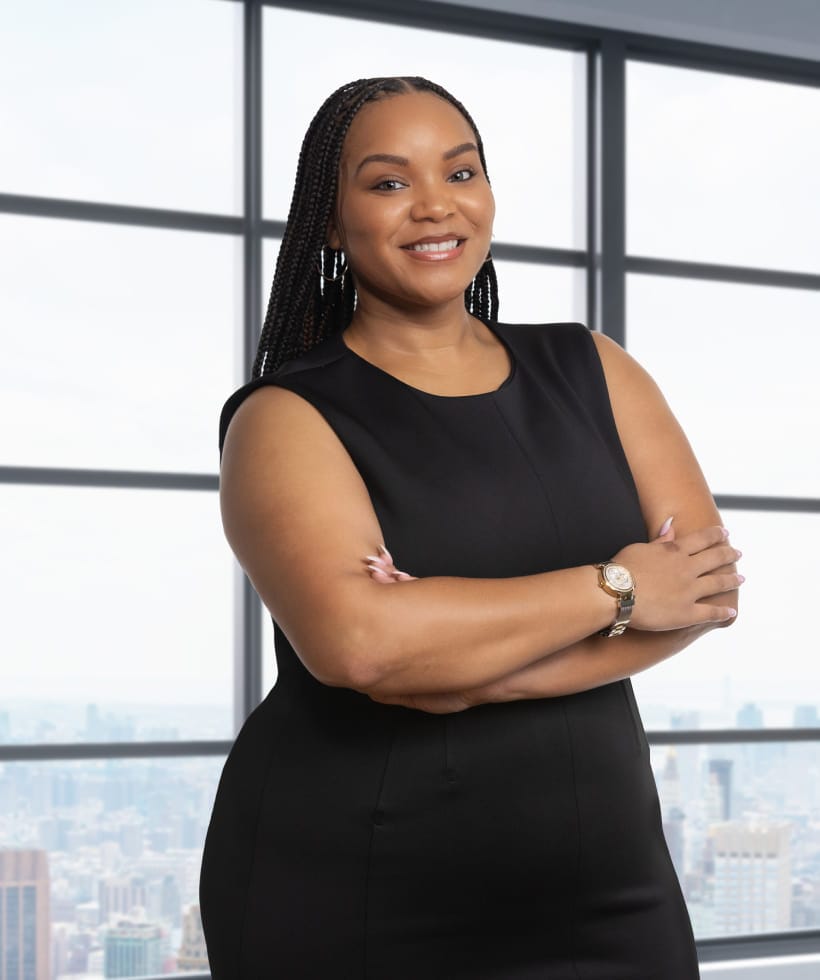 Jenaye Matthew's headshot. Jenaye is pictured smiling and wearing a black dress a watch and her arms crossed.
